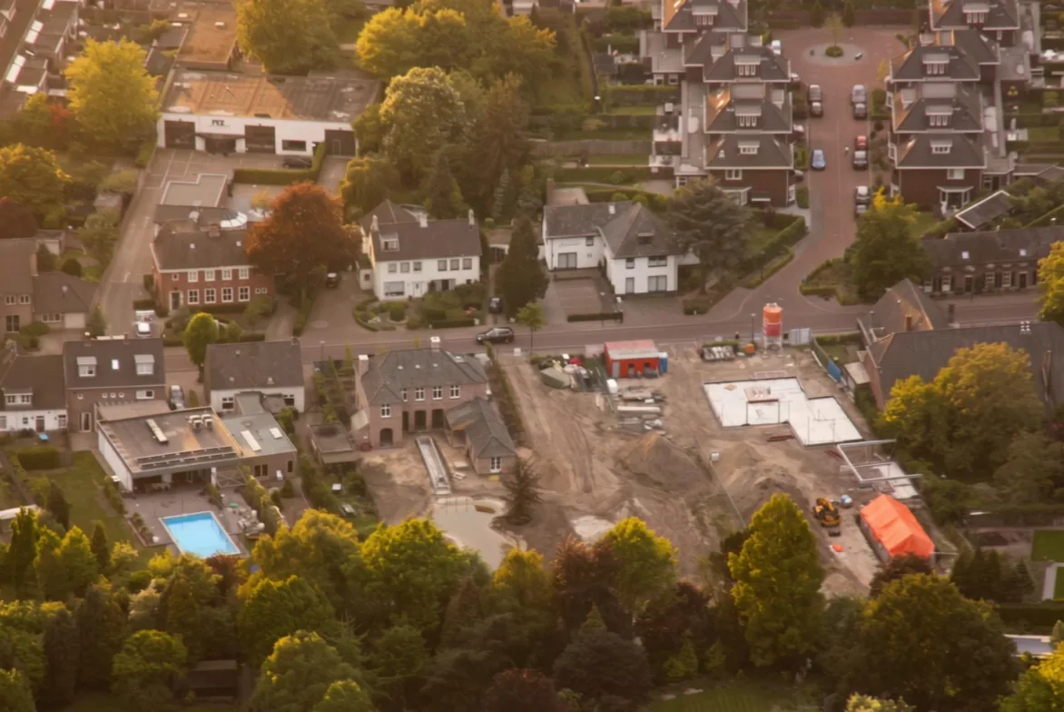 Luchtfoto van Nuenen in het avondlicht met de bouwkavel aan de Berg